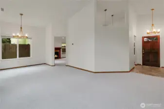 Spacious living room with vaulted ceilings, numerous windows, and dining area