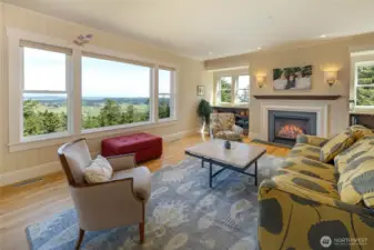 Warm and inviting living space centered around a fireplace, with expansive windows bringing in natural light and scenic views.