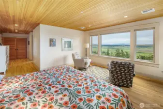 Expansive primary suite with warm wood ceilings, sitting area, and panoramic views of San Juan Valley and surrounding waterways.