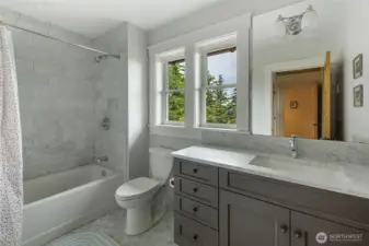 Light-filled guest bath with marble tile, modern fixtures, and quality finishes reflecting the home’s custom craftsmanship.