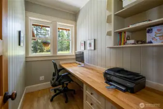 Dedicated home office with built-in desk and shelving, ideal for remote work in a quiet San Juan Island setting.