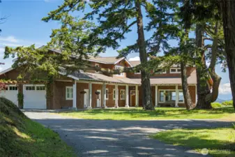 Classic island architecture with wraparound porch, set among mature trees for privacy and timeless curb appeal.
