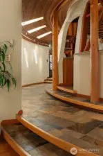 Slate floors and a wood inlaid staircase lead to a curved hallway that frames the striking central dome.