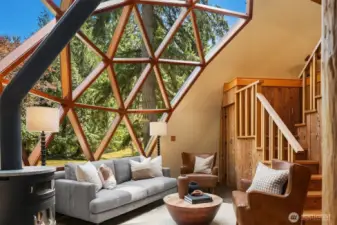 Floor-to-dome glass creates a breathtaking focal point, flooding the space with light. A staircase leads to an open loft overlooking the dome.