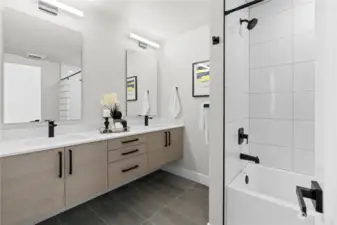 Elegant bathroom with dual vanities, sleek black fixtures, and a modern bathtub.