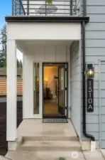 Welcome home. A sleek covered entry welcomes you in with modern lines and warm lighting—yes, that’s the first glimpse of your stunning new space just beyond the open door!