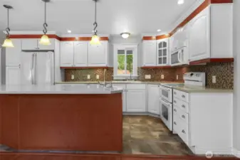Lovely kitchen with wonderful details! Crown molding, double oven, solid surface counter top, glass-door corner cabinet--and heated tile floors!