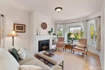 Cozy up by the wood fireplace in this lovely living room and enjoy all of the natural light pouring through the bay windows.