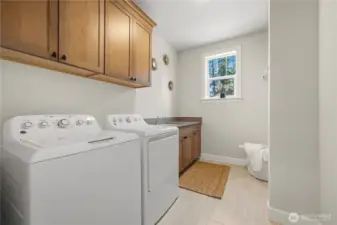 Convenient upper level laundry room with utility sink and cabinets.