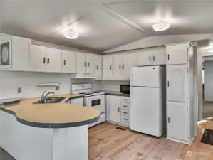 A bright and refreshed kitchen with newly painted cabinets featuring modern hardware. White appliances keep the space light and airy. The new flooring ties everything together beautifully.