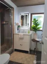 Large tiled shower, with tile details and wood ceiling for a custom touch.