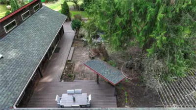 Private outdoor living space featuring an expansive deck perfect for dining and entertaining, seamlessly connected to a charming brick patio and beautifully landscaped surroundings. Nestled among mature trees, this peaceful setting offers multiple areas to relax, gather, and enjoy the natural beauty of the Pacific Northwest.