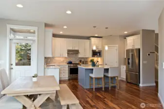 Beautiful kitchen with Quartz countertops and complimentary backsplash, counter depth KitchenAid Refrigerator and newer gas range (2025), and Bosch dishwasher.