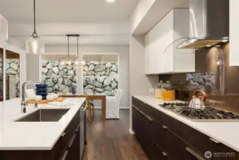 So much storage in the clean lined cabinetry. Gas range is on display with the rich slab backsplash and glass top hood.