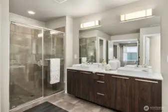 The spa-like Primary bath with tiled shower surround, tiled floors, and double vanities.