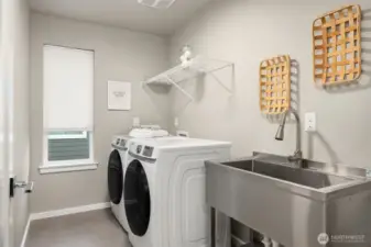 Generous laundry room with stainless steel farmhouse sink for added convenience.