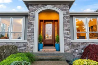 A warm, welcoming entry framed by stonework and custom glass doors, reflecting Zetterberg’s hallmark craftsmanship.