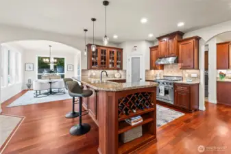 Open kitchen and dining with archways, hardwood flooring, wine storage, and unobstructed flow to the great room.