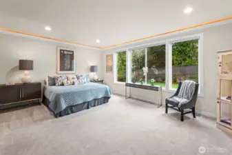 Expansive main-floor primary suite featuring garden views, tray lighting, and a restful, private atmosphere.