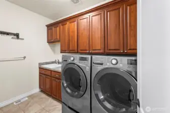 Main-floor laundry with extensive cabinetry, utility sink, and LG washer/dryer—organized and functional.