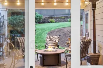 Covered patio with firepit, creating a cozy year-round outdoor living space overlooking peaceful, terraced gardens.