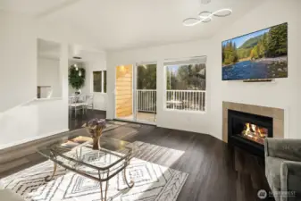A view from the front door looking into the living room, back deck area, and dining area! Cozy up to the gas  fireplace during the winter season! Nice laminate wood flooring throughout the house. This upstairs unit offers slight vaulted ceilings over the living room.