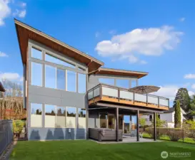 Water side of the home. Upper outside living area, lower covered patio w/ hot tub and fully fenced yard.
