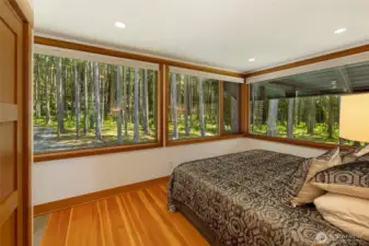 The back primary bedroom takes in the beauty of the surrounding woods, giving the feeling of living in a treehouse.