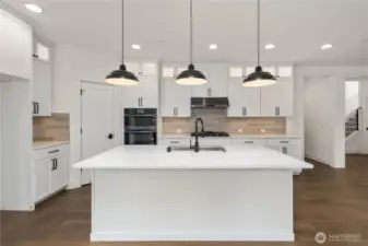 Kitchen Island:  A generous quartz island sits at the center of the kitchen, paired with matte black pendants that give the space a bold, contemporary feel. The island’s size and layout provide room for prep work, serving, or casual seating, all while keeping the cook connected to the rest of the main floor. With its location in Bothell’s sought-after Canyon Park corridor, daily errands, dining options, and Northshore schools are all close at hand. This island becomes a natural gathering point, blending function and design for effortless Northwest living.    These photos are from Lot 5 at Gooden Hollow, which is the same floorplan, but a different home than listed here. However, other homes in the community will have changes, so all photos, renderings, site maps, and floorplans are for visualization purposes only. Plans, colors, building orientation, finishes, home outlook, and other details can and WILL vary.