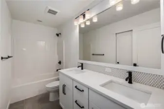 Upper-Level Full Bathroom:  This well-appointed full bath blends modern styling with everyday functionality, featuring a long quartz-topped dual-sink vanity, matte black hardware, and a full-height mirror that brightens the space. The wide layout supports easy morning routines, while the tiled flooring and thoughtful storage keep the room feeling tidy and efficient. Located in the heart of Bothell’s Canyon Park area, the home places you minutes from local trails, cafés, and schools while maintaining excellent access to I-405. Subtle details—like the penny-tile backsplash and streamlined lighting—add a polished, elevated feel that complements the rest of the home.    These photos are from Lot 5 at Gooden Hollow, which is the same floorplan, but a different home than listed here. However, other homes in the community will have changes, so all photos, renderings, site maps, and floorplans are for visualization purposes only. Plans, colors, building orientation, finishes, home outlook, and