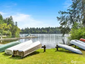 Summer view of the lake & spots to stow your boat & kayaks. The swim area offers a large dock and slide. There are a few beach areas to enjoy in the community