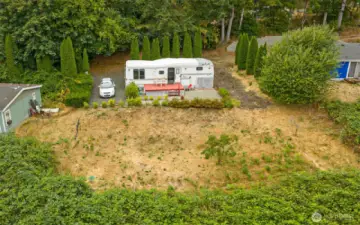 This partially sloped lot offers a broad, level area at the top, providing versatile space for future use, while the drainfield rests on the lower section.