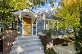 Shingled façade with sculptural entry and landscaped approach—welcoming curb appeal under mature trees.