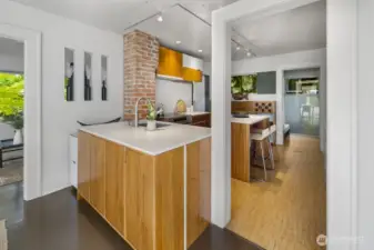 Streamlined kitchen with central prep island, brick detail, and adjacent breakfast bar for casual meals.