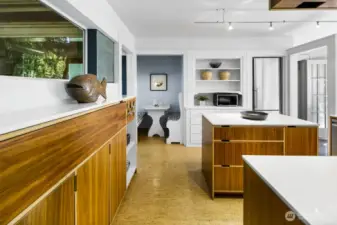 Wall of custom storage and island keep essentials organized; open view into the breakfast nook.