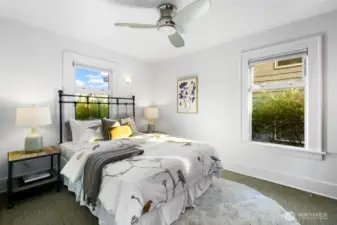 Main-floor bedroom with dual windows, ceiling fan, and soft carpet for a quiet retreat.