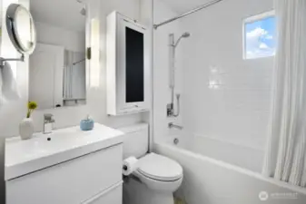 Bright full bath with subway-tile surround, soaking tub, and stowaway vanity table.