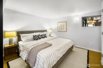 Quiet lower-level bedroom sized for a king, with soft lighting and a daylight window.
