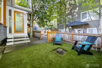 Fenced, easy-care lawn with seating; steps from a frosted-glass side entry.