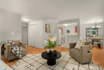 Living room with dining area on the right, kitchen in the middle, coat closet door in hallway and bedroom 2 in the background on the left.