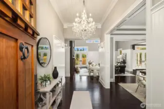 Grand entrance through a custom walnut door and statement chandeliers.