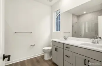 Primary bath with double sink vanity and large walk-in shower with bench.