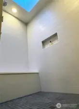 Shower surround in guest bath with niche, bench, and skylight.