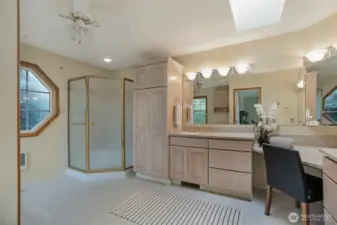 Expansive primary en suite offers a spa-like experience with dual vanities, ample cabinetry for all your essentials, and a dedicated makeup station. A skylight and octagon window fill the space with soft natural light.