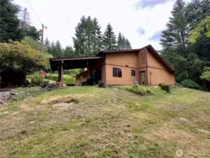 Side yard and view towards the covered patio of the single level home at 818 NW 349th St, La Center WA in Clark County. Pond area on beyond patio left side of the photo.