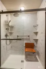 Beautiful new primary suite shower with bright lighting, built in seat, and easy access.