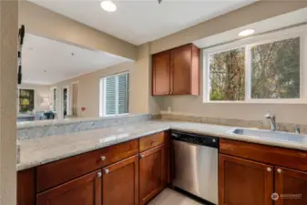 Bright and functional U-shaped kitchen with granite countertops, stainless steel appliances, and a lovely view of the surrounding trees. Perfectly designed for cooking and entertaining in style!