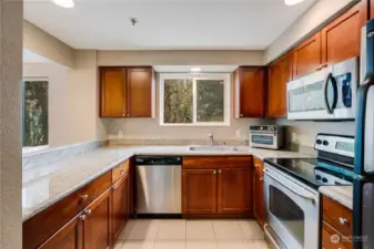 Bright and functional U-shaped kitchen with granite countertops, stainless steel appliances, and a lovely view of the surrounding trees. Perfectly designed for cooking and entertaining in style!