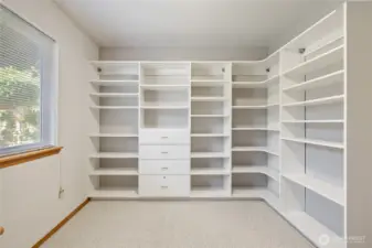 One bedroom currently being used as an office featuring crisp white built-ins for organized storage.