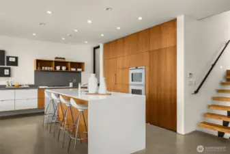 A chef’s stage: waterfall island, sculptural cabinetry, and the prestige of Sub-Zero, Miele, and Gaggenau — cooking here becomes performance art.